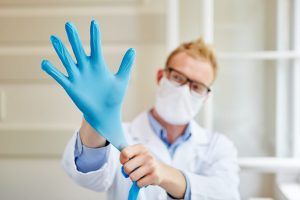 Arzt zieht sich Handschuhe an